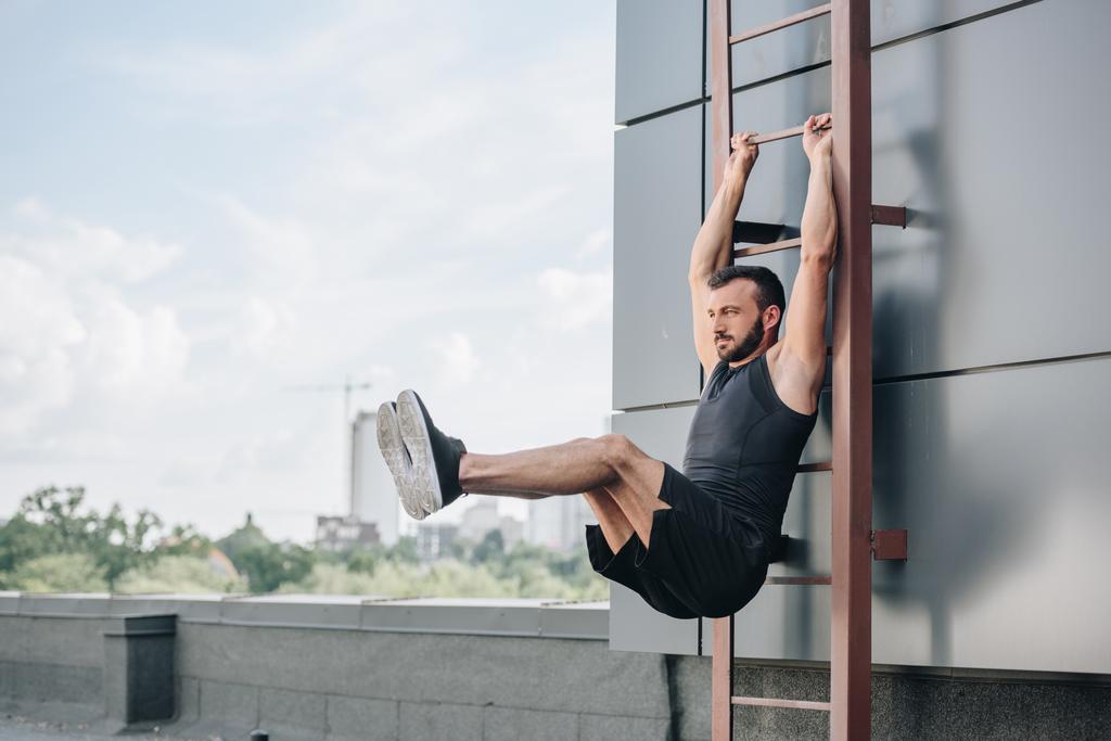 Przystojny sportowiec robi nogę podnosi na drabinie na dachu - Zdjęcie, obraz