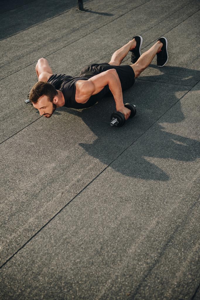 красивий спортсмен робить поштовхи з гантелями на даху
 - Фото, зображення