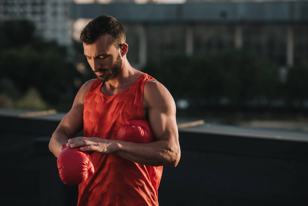 handsome sportsman wearing boxing glove on roof - Photo, Image
