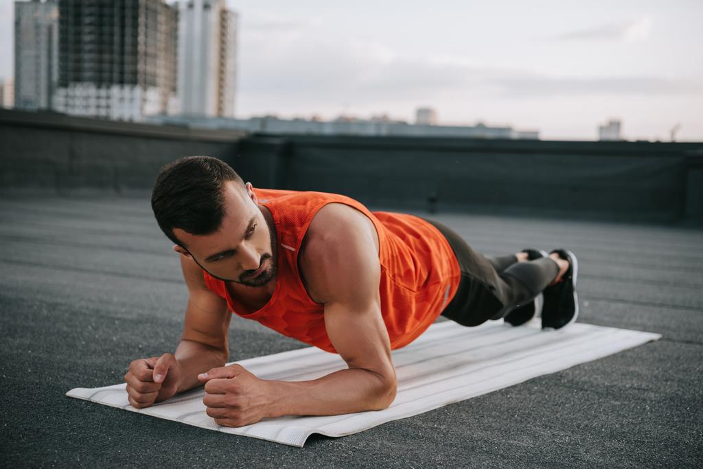 jóképű sportoló csinál jóga matracot a tető deszka - Fotó, kép