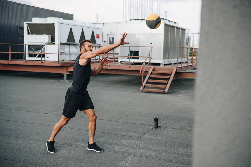 schöner Sportler fängt Medizinball auf Dach - Foto, Bild