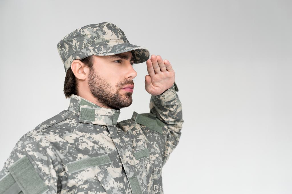 vue latérale d'un soldat barbu confiant en uniforme militaire saluant sur fond gris
 - Photo, image