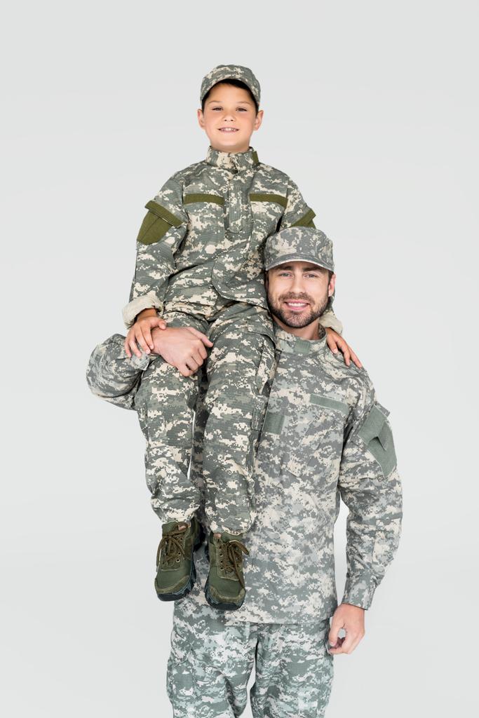усміхнений солдат тримає сина у військовій формі на плечі ізольовано на сірому
 - Фото, зображення