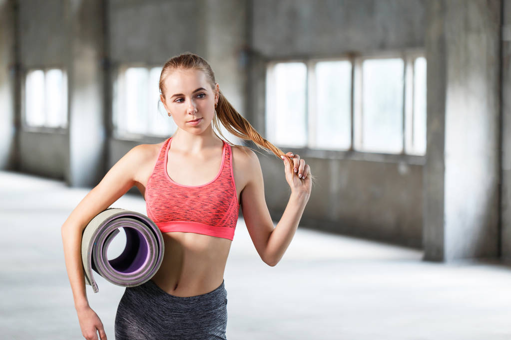 Retrato de chica en forma sosteniendo alfombra deportiva en el gimnasio
 - Foto, Imagen