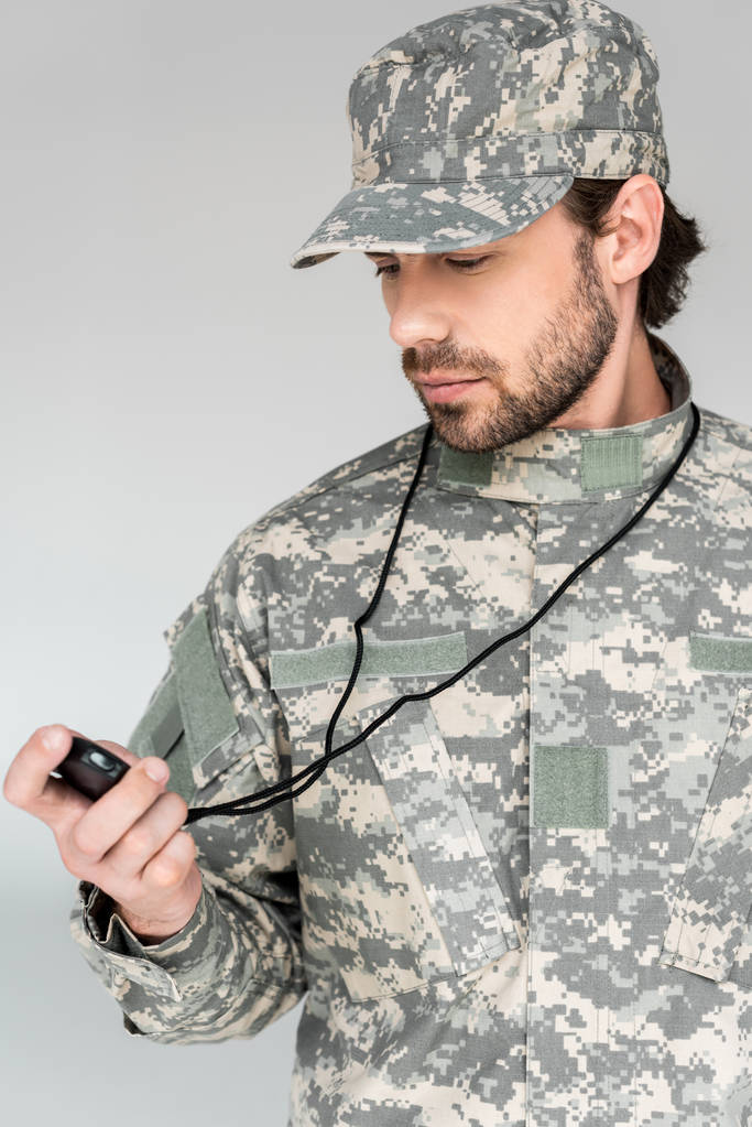πορτρέτο του στρατιώτη στη στρατιωτική στολή με stop watch σε γκρίζο φόντο - Φωτογραφία, εικόνα