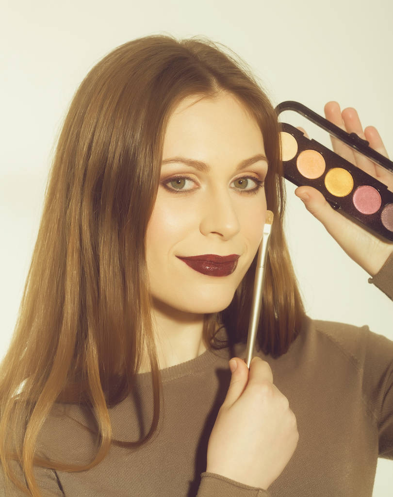 Chica sonriente aplicando maquillaje en la cara bonita con cepillo
 - Foto, Imagen