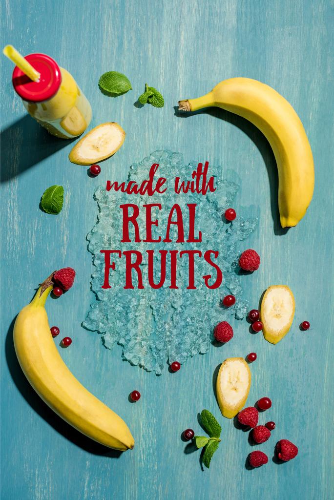κάτοψη του μπουκαλιού με smoothie νωπή μπανάνα και μούρα με φύλλα μέντας, με την επιγραφή «γίνονται με πραγματικά φρούτα» - Φωτογραφία, εικόνα