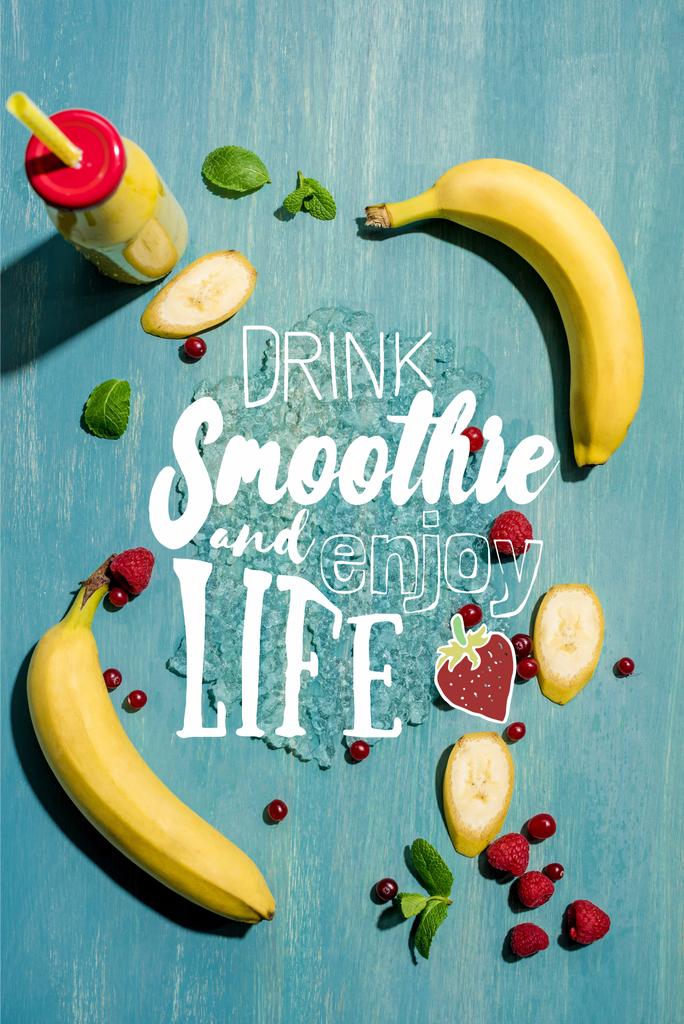 Draufsicht auf Flasche mit frischem Bananen-Smoothie und Beeren mit Minzblättern, mit Schriftzug "Drink Smoothie und genieße das Leben" - Foto, Bild