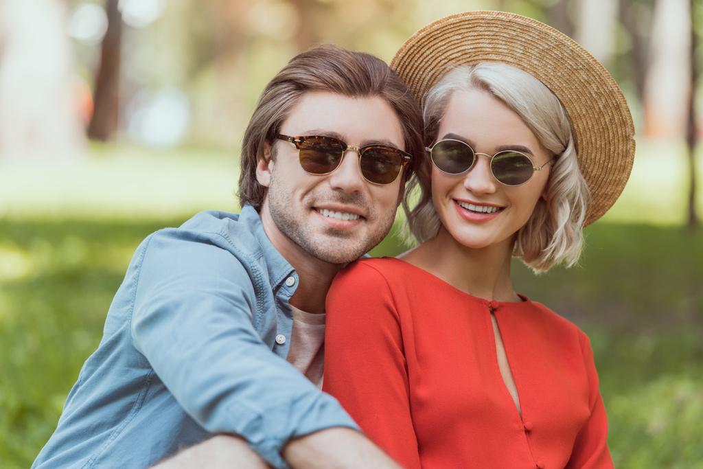 portrait of couple in sunglasses looking at camera in park - Photo, Image