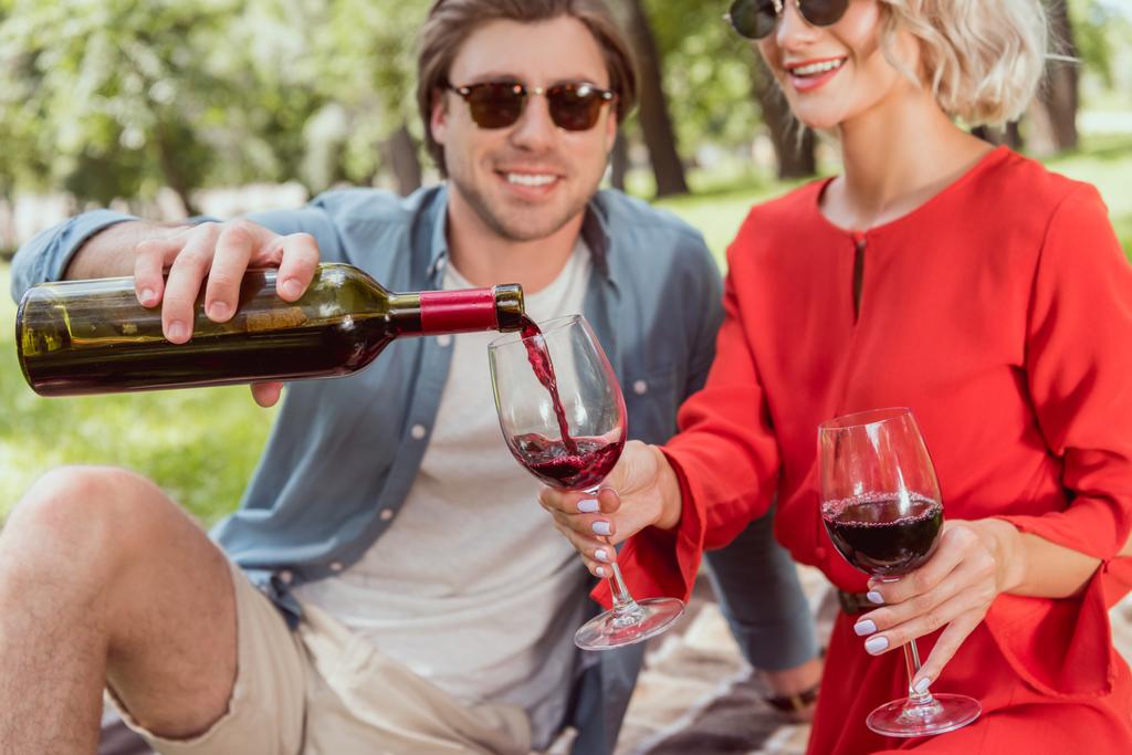 petit ami heureux verser du vin rouge dans des verres dans le parc
 - Photo, image