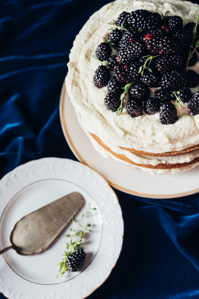 високий кут зору свіжоспечений ожиновий торт з тарілкою та сервером для торта синя тканина
 - Фото, зображення