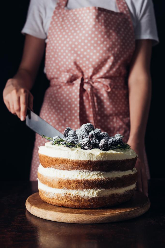 黒にピンクのエプロン切削おいしいブラックベリーのケーキで女性のクロップ撮影 - 写真・画像