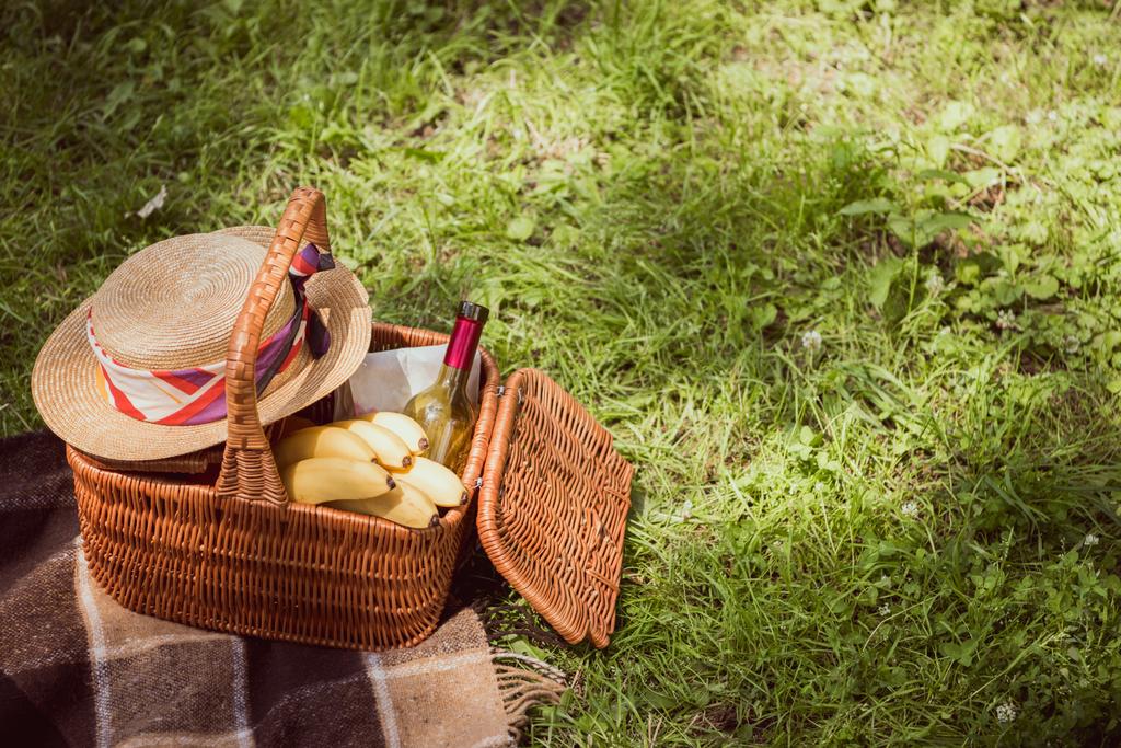 Picknickkorb mit Bananen und einer Flasche Wein im Park - Foto, Bild