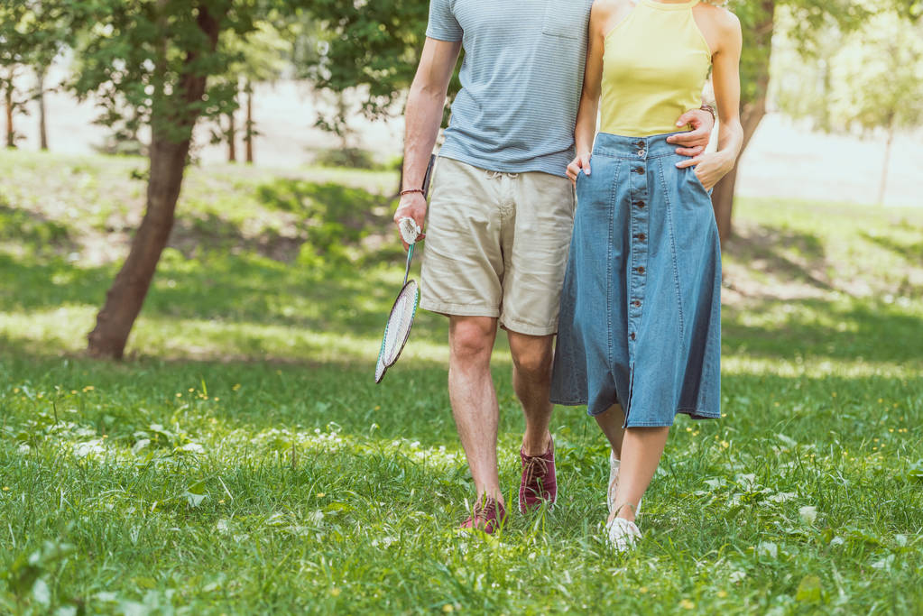 バドミントンのラケットと羽根公園でプレーする歩くカップルの画像をトリミング - 写真・画像
