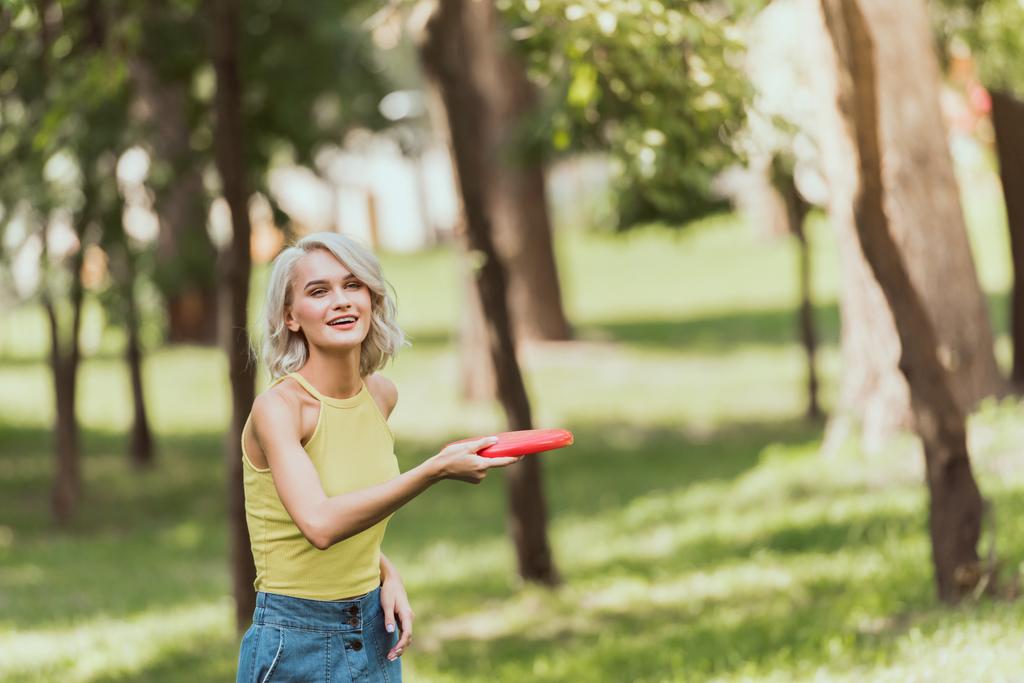 schönes Mädchen wirft Frisbee-Scheibe in Park  - Foto, Bild