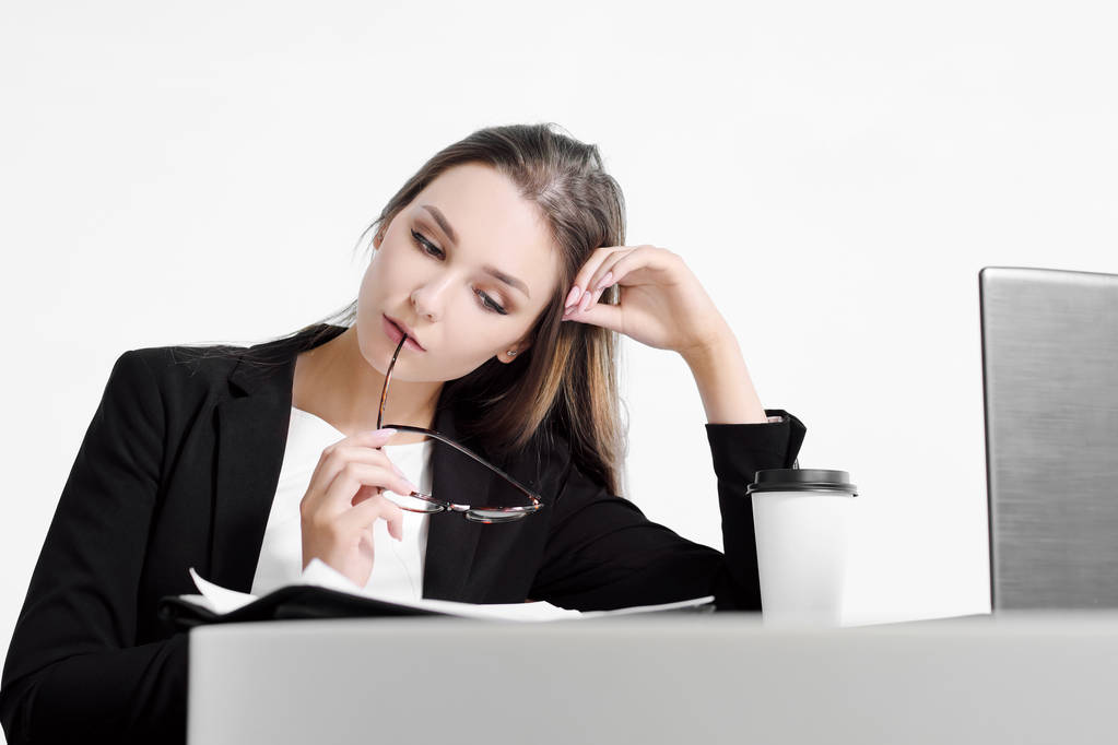 Podnikatel dívka sedí u stolu v kanceláři a práci na notebooku na bílém pozadí. - Fotografie, Obrázek