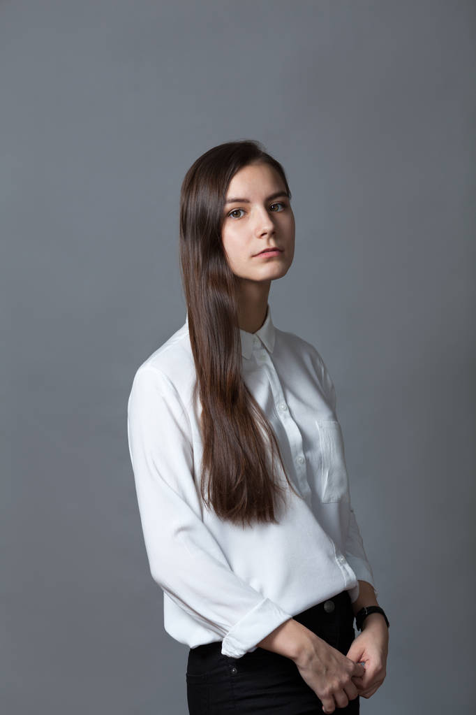 Porträt eines glücklichen netten Schulmädchens Teenager in weißem Hemd auf grauem Hintergrund, Studio - Foto, Bild
