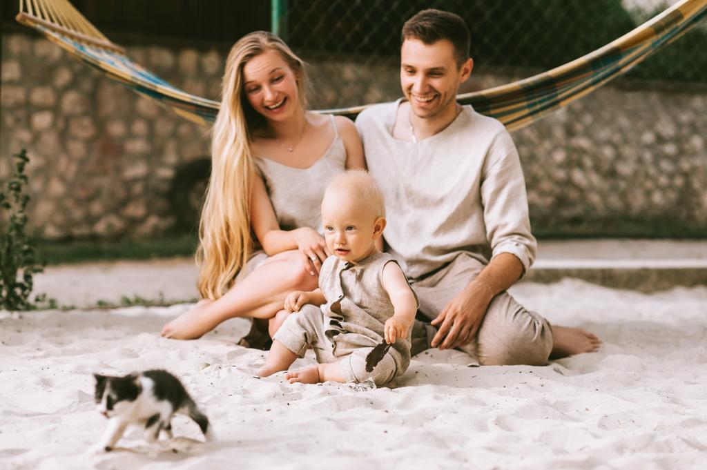 heureux famille avec petit fils et chaton assis sur le sable avec hamac derrière à la campagne
 - Photo, image