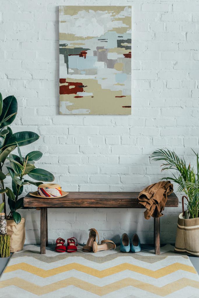 Verschiedene Schuhe unter Holzbank im Hausflur, Malerei an der Wand - Foto, Bild