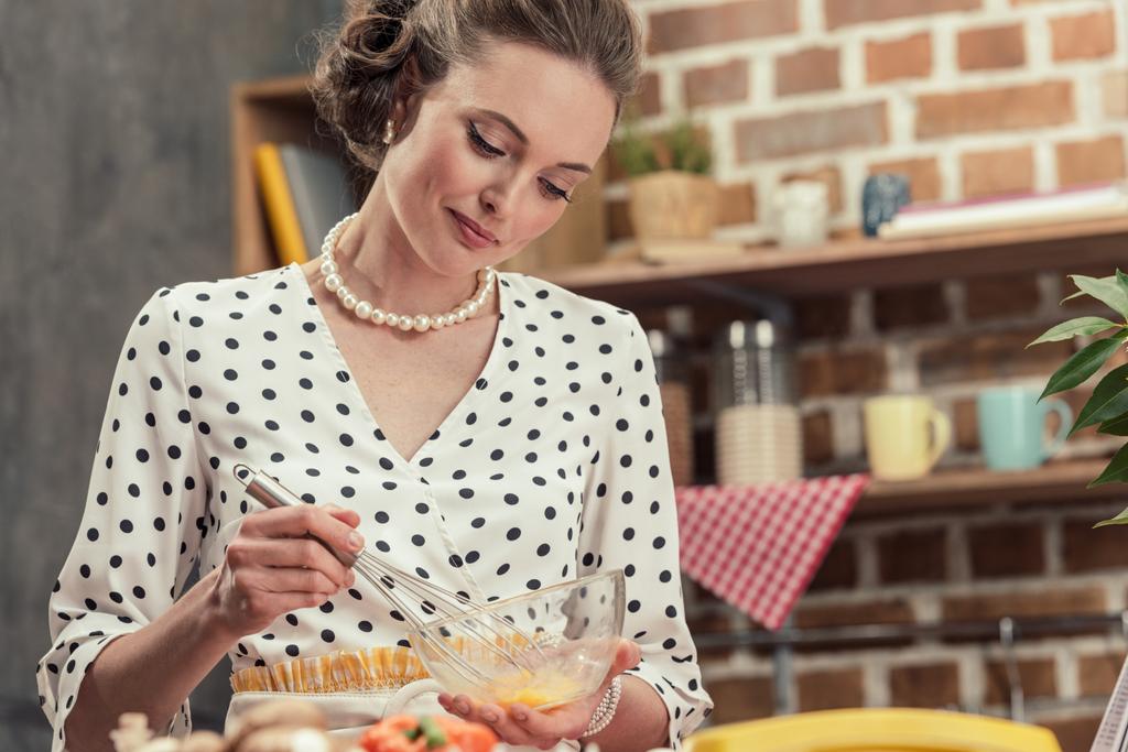glückliche erwachsene Hausfrau, die Eier für Omelette in der Küche schlägt - Foto, Bild