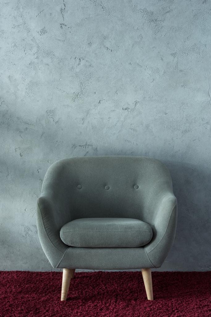 szary fotel na bordowy dywan w pobliżu szare ściany w biurze - Zdjęcie, obraz