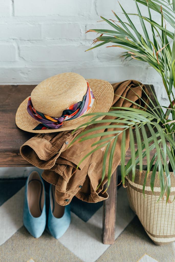 ψάθινο καπέλο και σακάκι σε ξύλινο παγκάκι στο διάδρομο - Φωτογραφία, εικόνα