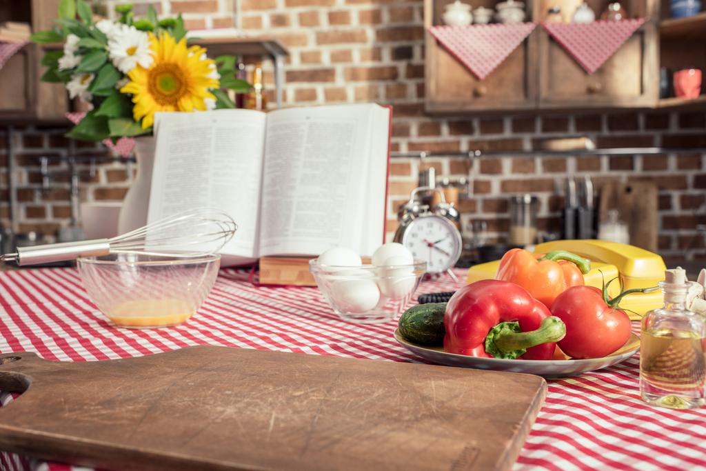 verschillende ongekookte producten en receptenboek op tafel bij de keuken koken - Foto, afbeelding