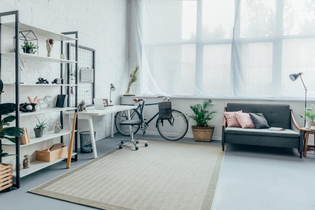 interieur van een woonkamer met fiets, tabel, planken en slaapbank - Foto, afbeelding