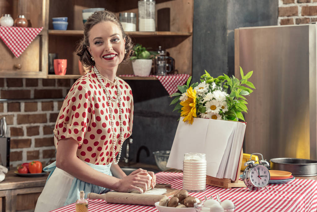 sorrindo adulto dona de casa amassar massa com as mãos e olhando para a cozinha
 - Foto, Imagem