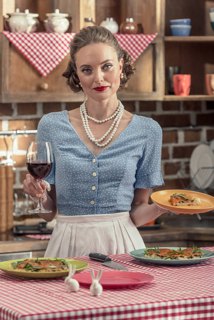 kadeh kırmızı şarap ve mutfak at taze pişmiş kek ile güzel yetişkin ev kadını - Fotoğraf, Görsel