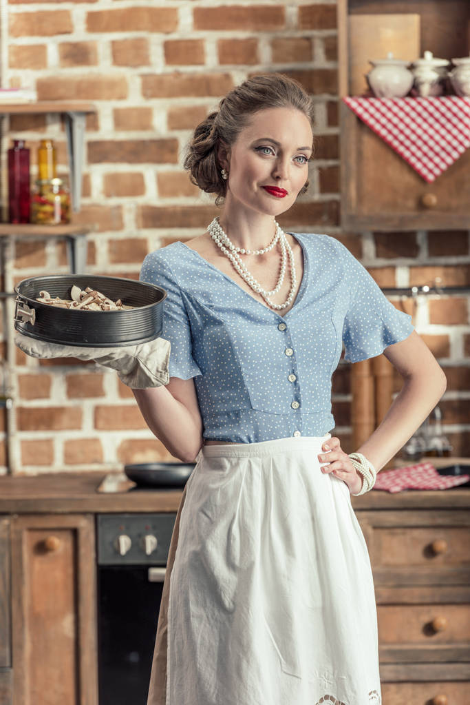 красивая взрослая домохозяйка держит выпечку Трей на кухне
 - Фото, изображение