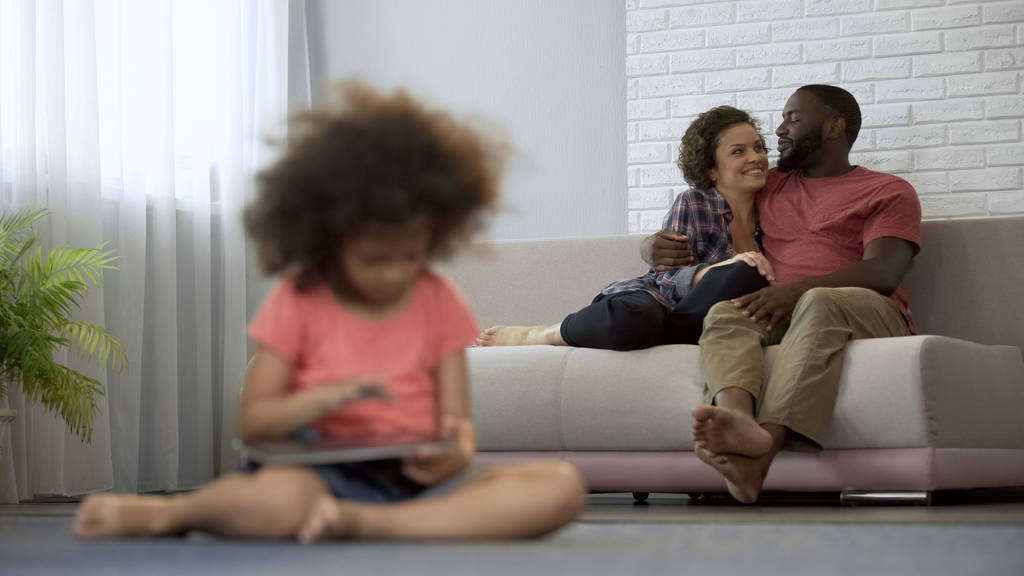 Fiatal szülők élvezi a közös időtöltése néz lányuk játszik a tabletta - Fotó, kép