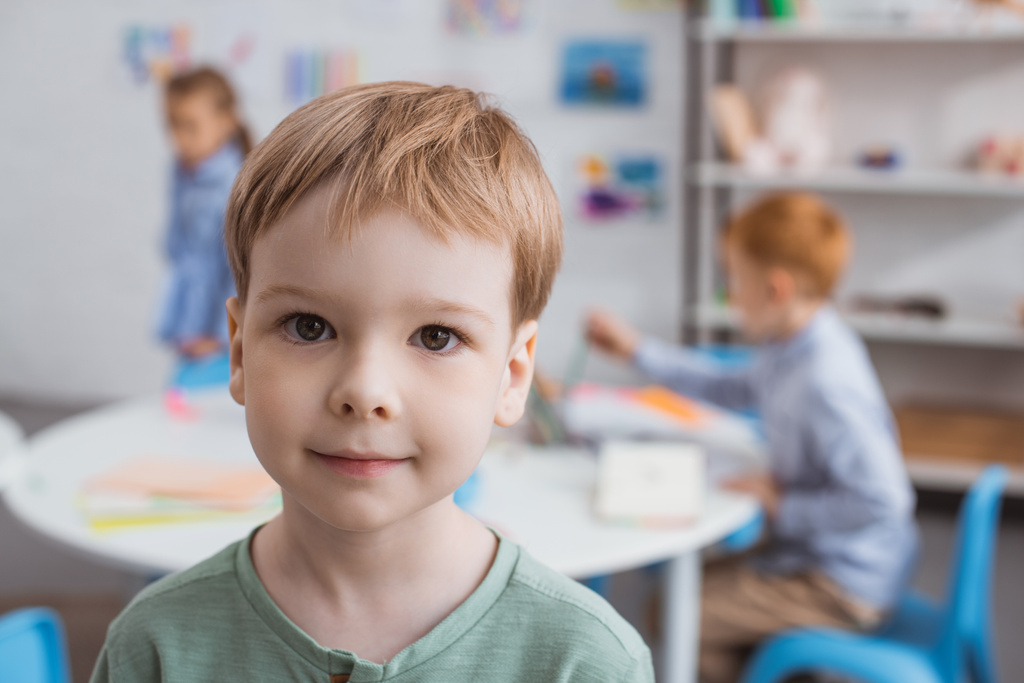 foyer sélectif de mignon petit garçon regardant caméra avec des camarades de classe derrière dans la salle de classe
 - Photo, image
