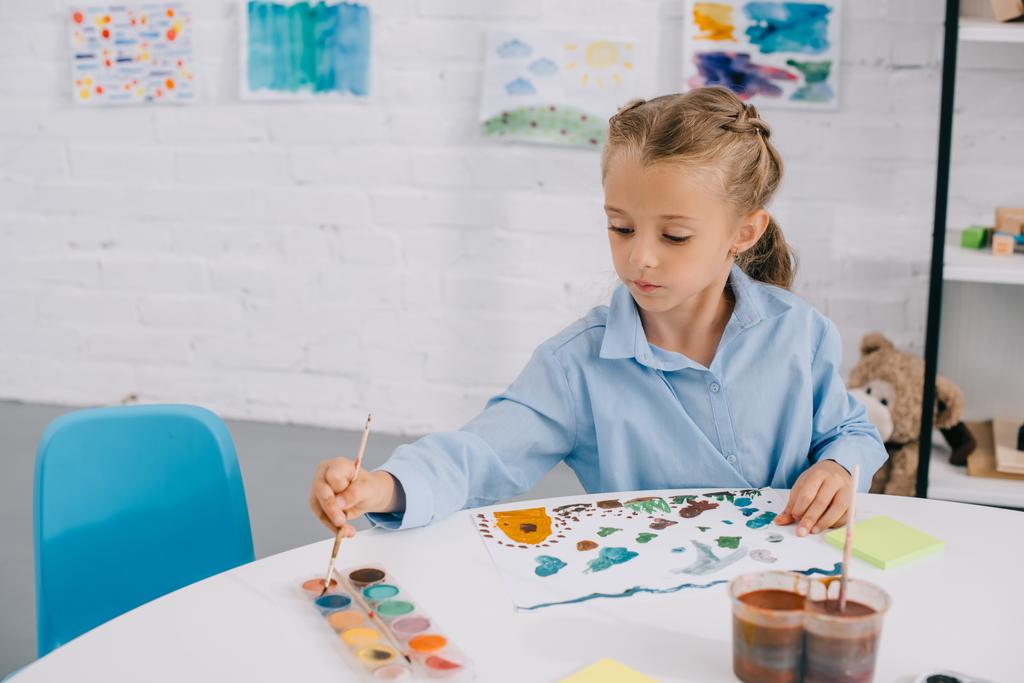 retrato de adorável criança focada desenho colorido quadro com tintas e escova à mesa
 - Foto, Imagem