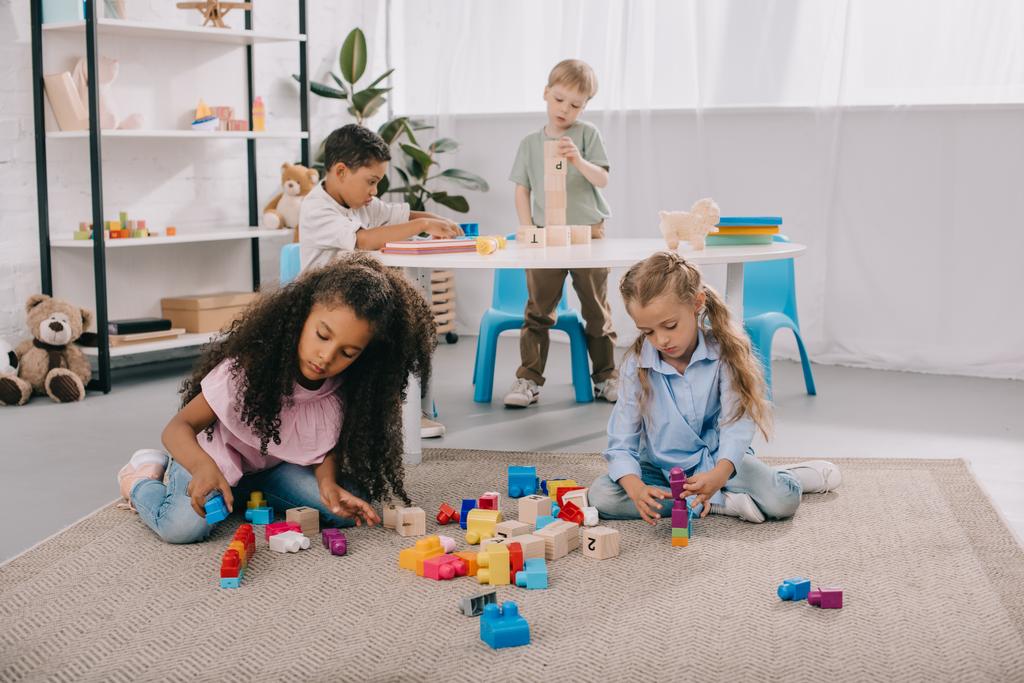 bambini in età prescolare multietnica concentrati che giocano con blocchi di legno in classe
 - Foto, immagini