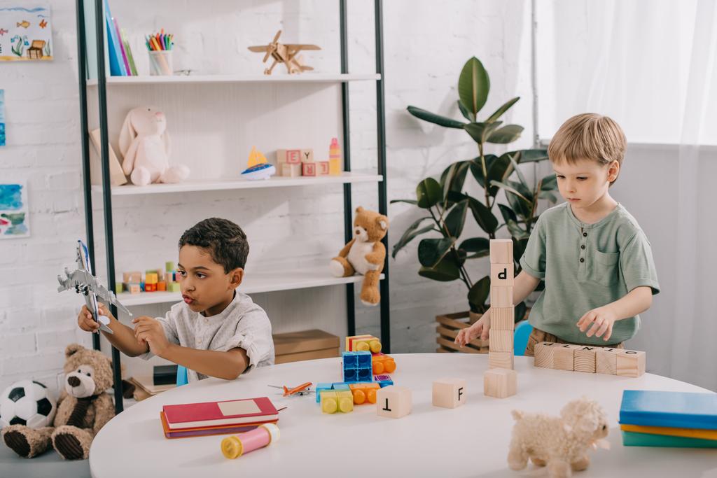 chicos multiculturales jugando con juguetes en el aula
 - Foto, Imagen