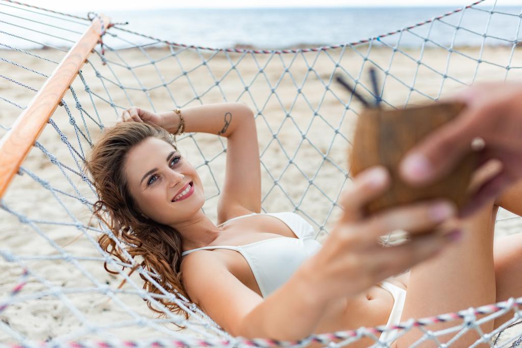 selective focus of man giving coconut cocktail to his attractive girlfriend on hammock - Photo, Image