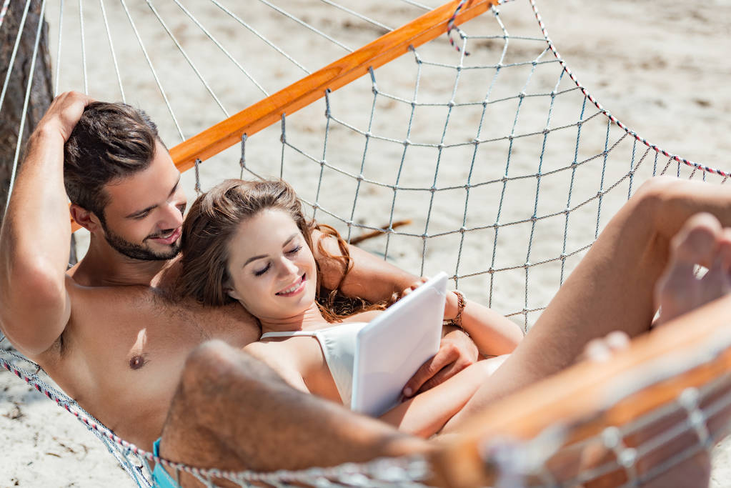 gülümseyen çift dijital tablet hamak plajında dinlenirken kullanma - Fotoğraf, Görsel