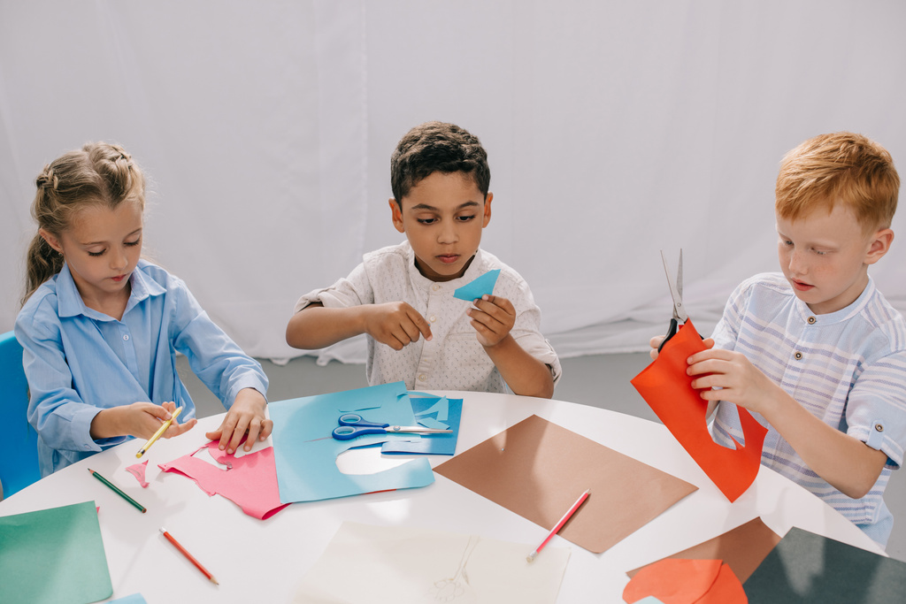 focado crianças multirraciais fazendo papel applique em sala de aula
 - Foto, Imagem