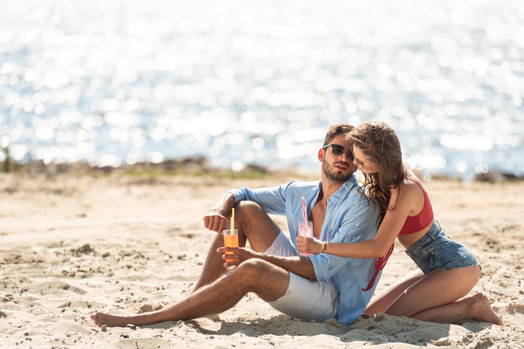pareja con cócteles sentados en la playa cerca del mar en verano
 - Foto, imagen