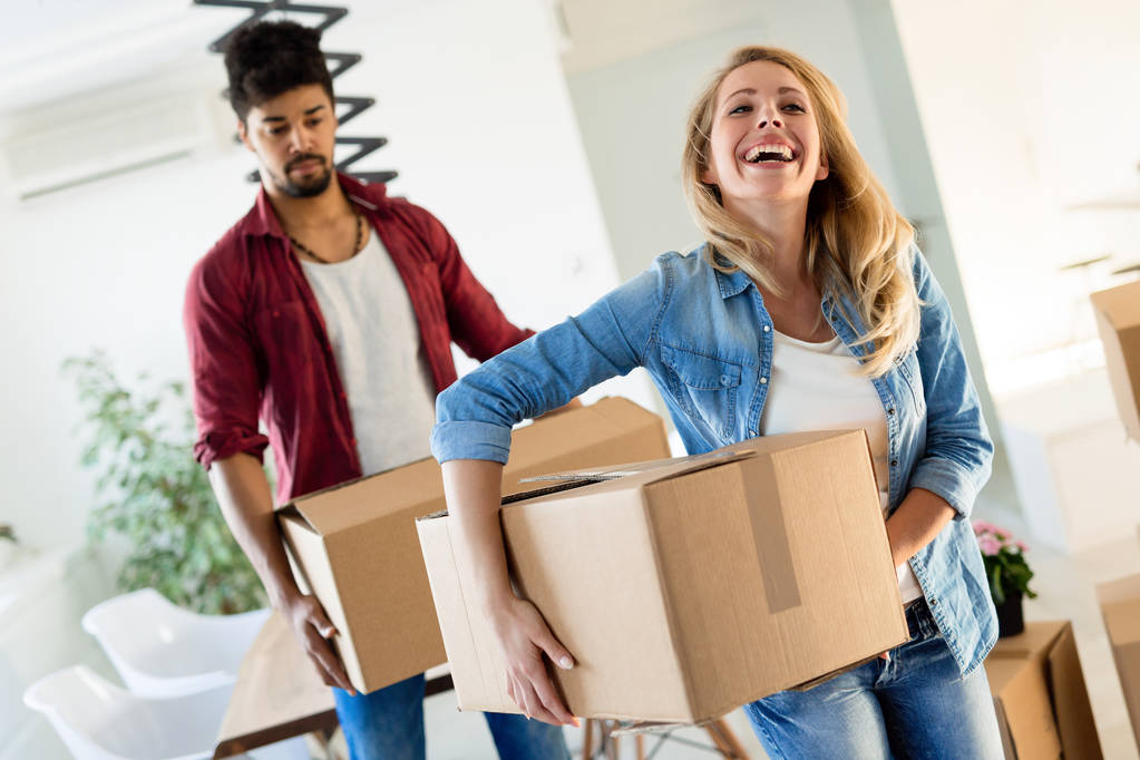 Молода пара закоханих розпаковує картонні коробки в новому будинку, рухаючись в концепції
 - Фото, зображення