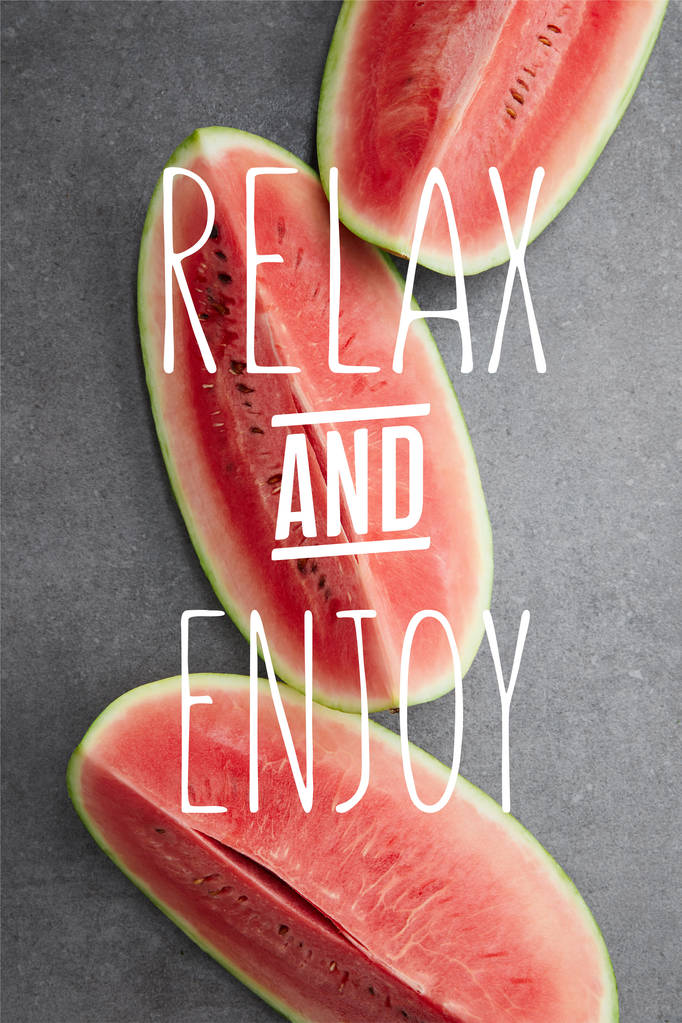 flache Liege mit Wassermelonenstücken auf grauer Betonplatte, mit Schriftzug "Relax and enjoy" - Foto, Bild
