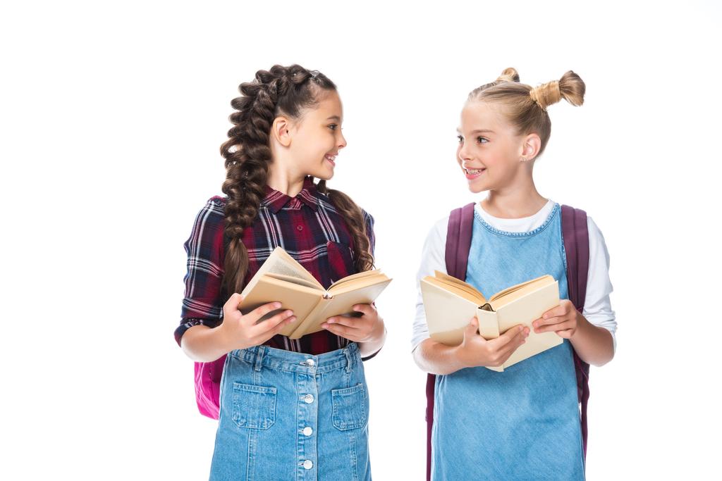 dzieci w wieku szkolnym gospodarstwa otworzyć książki i patrząc na siebie nawzajem na białym tle - Zdjęcie, obraz