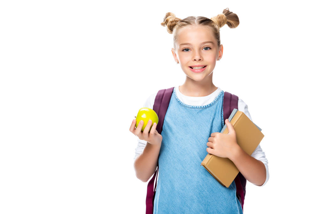 улыбающийся школьник держит яблоко и книги изолированы на белом
 - Фото, изображение
