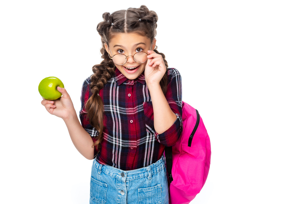 školák drží zralé jablíčko a při pohledu na fotoaparát nad brýlemi izolované na bílém - Fotografie, Obrázek