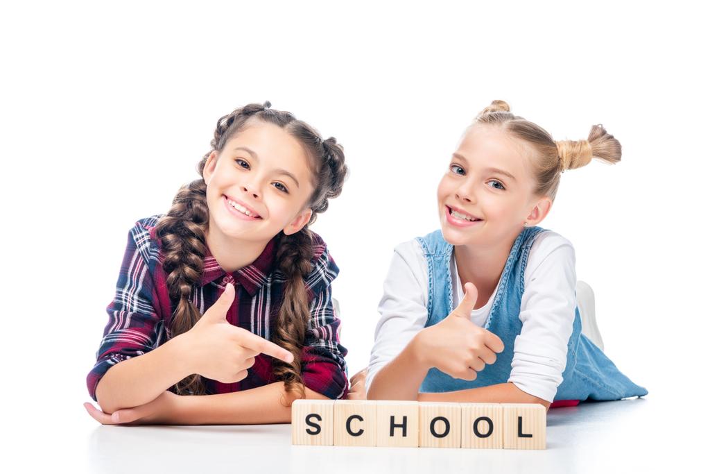žáků, které ukazuje palec do dřevěných kostek s slovo školy izolované na bílém - Fotografie, Obrázek