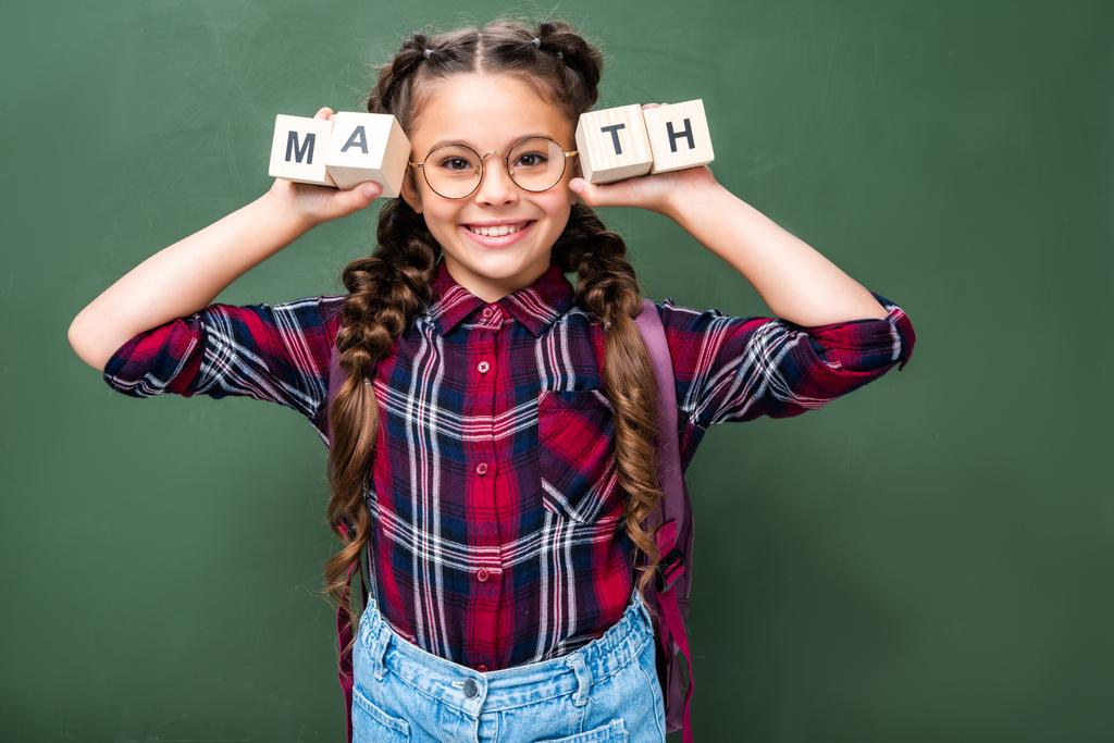 黒板近く単語数学の木製キューブを保持している小学生の笑顔 - 写真・画像