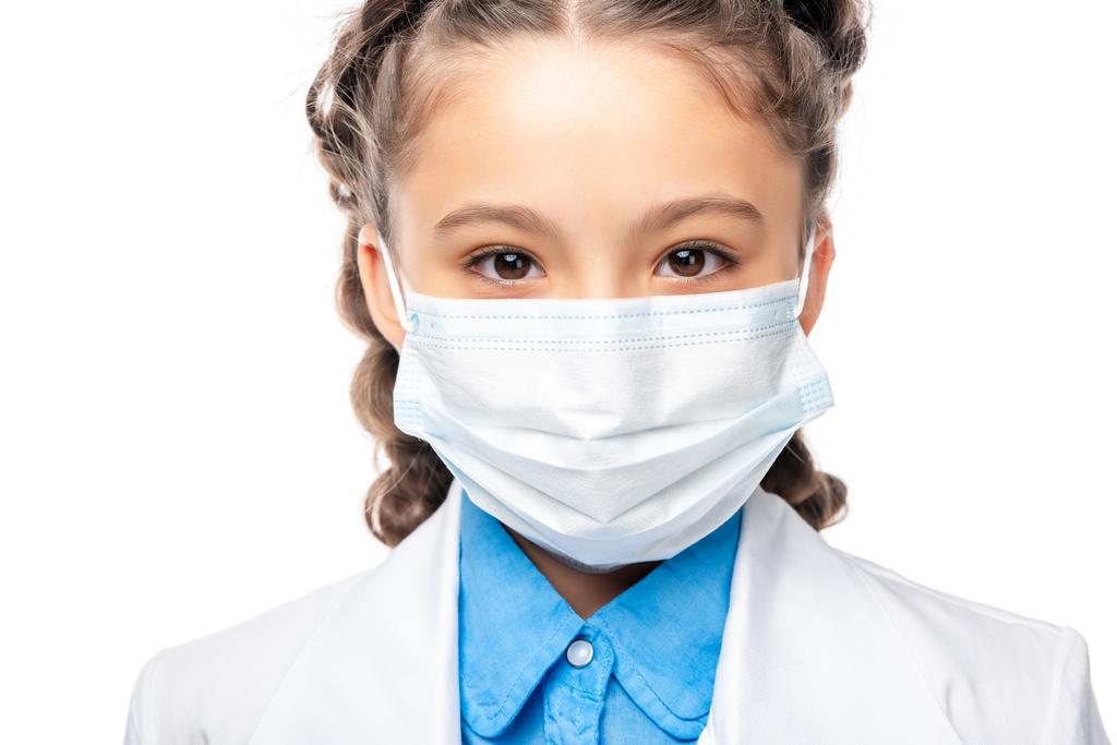 školák v lékařské masky při pohledu na fotoaparát izolované na bílém - Fotografie, Obrázek