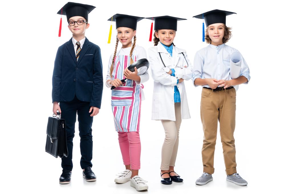 escolares con disfraces de diferentes profesiones y gorras de graduación mirando a la cámara aislada en blanco
 - Foto, imagen