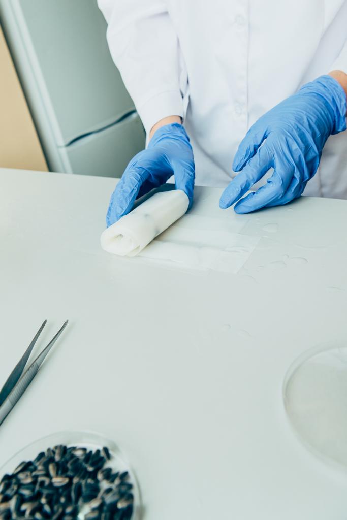 vista parcial del científico en guantes de látex trabajando en la mesa en laboratorio moderno
  - Foto, Imagen